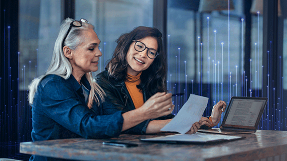 Two female employees discussing work in office