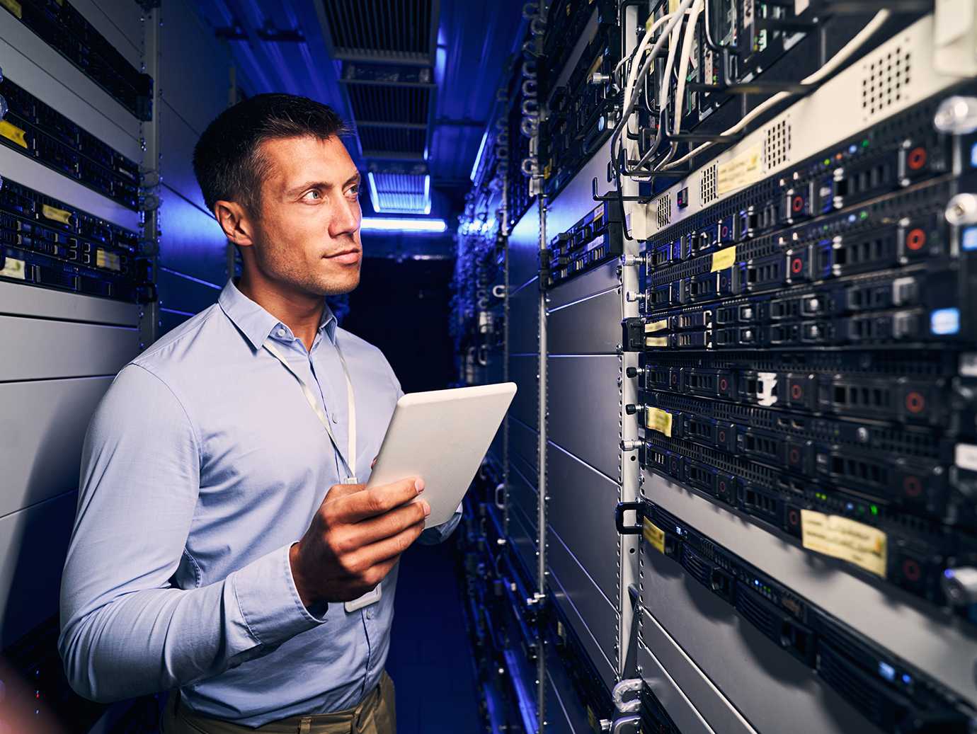A person holding a tablet in a server room